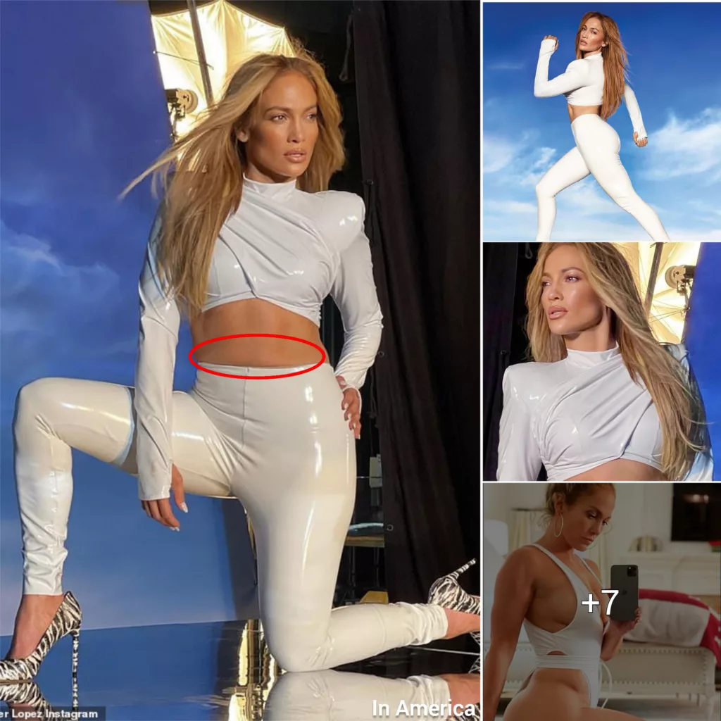 Jennifer Lopez showcases her rock solid abs in a curve-hugging white patent leather crop top and leggings